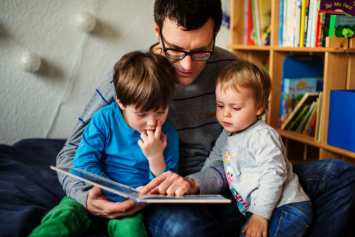 dad reading books with toddler girl and son