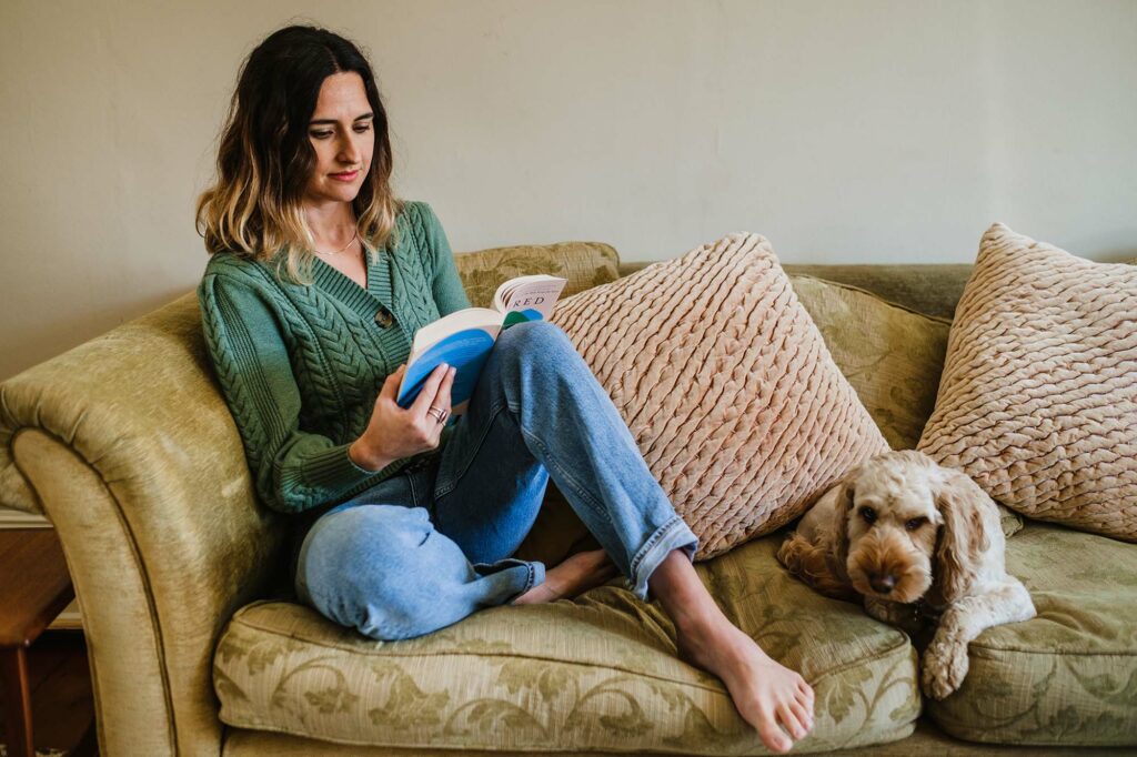 woman on couch reading with dog Mim