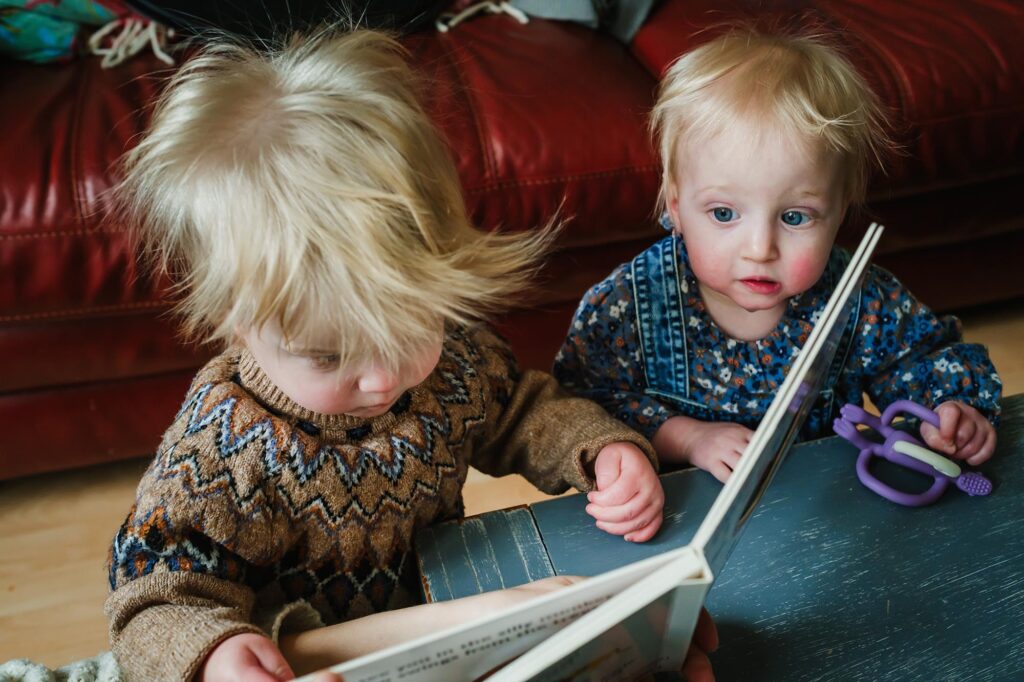 twin toddlers reading a book